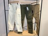 trois pantalons pour homme suspendus à un portant dans un magasin de vêtements