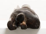 a statue of an elephant laying down on a white surface