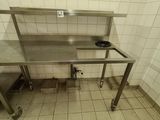 a stainless steel table in the middle of a tiled room