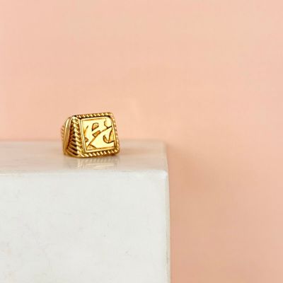 un gros plan d'une bague en or posée sur un bloc de marbre