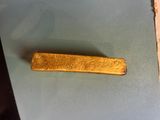 a piece of gold sitting on a table next to a piece of paper