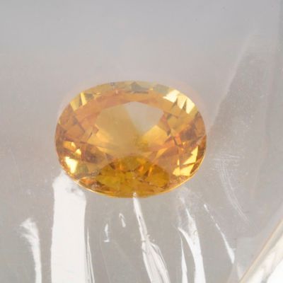 an oval cut yellow sapphire sitting on top of a white surface