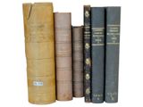several old books are lined up in a row on a white surface