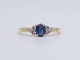 a close up of a blue sapphire and diamond ring on a white surface