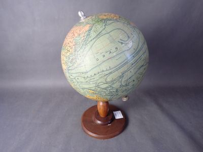 un petit globe terrestre posé sur un socle en bois, sur fond gris