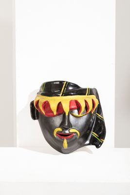 un masque noir et jaune exposé sur une étagère blanche