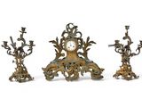 three antique clocks sitting next to each other on a white surface