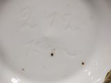 a close up of a white and gold plate with a flower on it