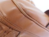 a close up of a brown leather bag on a white surface