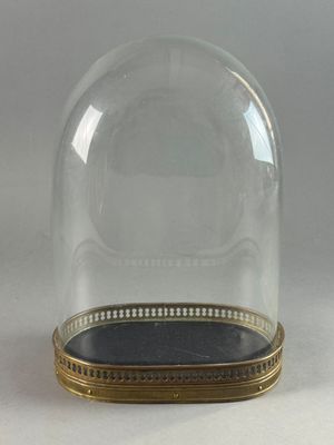 a glass clochet with a gold base on a white surface