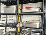 une grande étagère métallique sur laquelle sont posés de nombreux récipients et casseroles