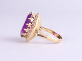 a close up of a gold ring with a purple stone in it