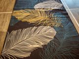 a black rug with white and gold feathers on it