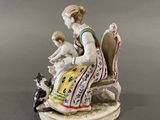 a figurine of a woman sitting on a chair with a dog