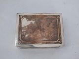 an old silver box with a painting on it sitting on a table