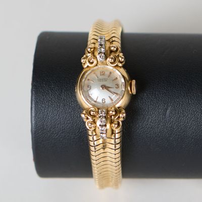 un gros plan d'une montre en or posée sur une bague noire