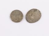 two silver coins sitting next to each other on a white surface