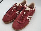 une paire de baskets rouges et blanches posées sur une surface blanche