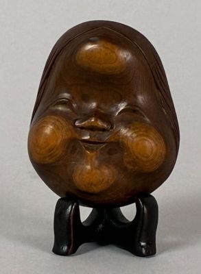 a small wooden sculpture of a laughing face on a stand