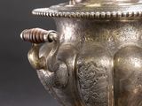 an antique silver vase with a lid and handles on a gray background