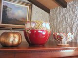 a red vase sitting on top of a table next to a gold pumpkin