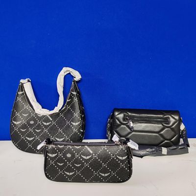 three pieces of black purses on a white table against a blue wall