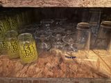 many glasses and jars sitting on a shelf in a room