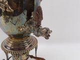 a silver vase on a stand with a bird on it