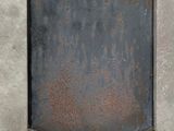 rusty metal plate on a concrete wall with a hole in the middle