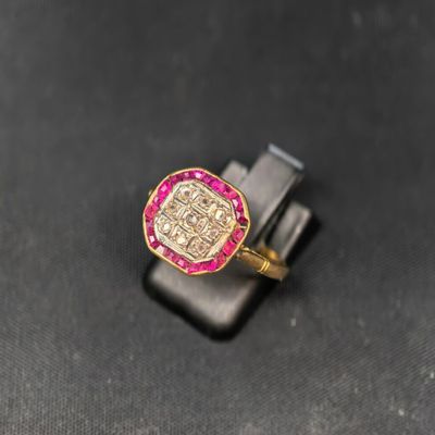 un gros plan d'une bague en or sertie de pierres roses sur un fond noir