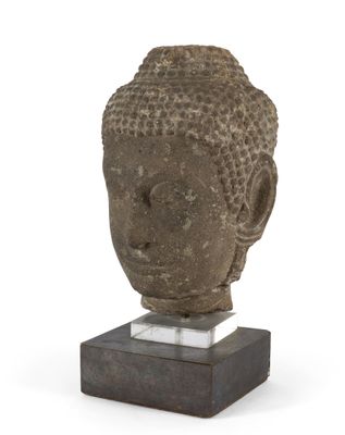 une image représentant une tête de Bouddha en pierre posée sur un socle en marbre