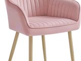 Le fauteuil en velours rose est recouvert de tissu et possède des pieds dorés.