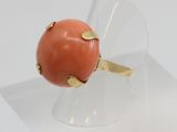 coral and gold ring on clear acrylic stand