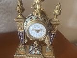 une horloge posée sur une table, surmontée d'une statue