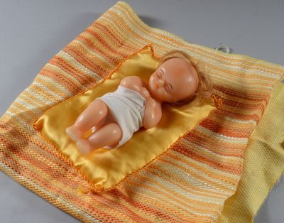 une poupée allongée sur une couverture posée sur une table