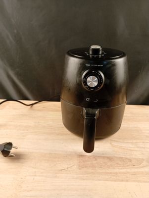 une friteuse à air chaud noire posée sur une table en bois