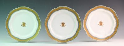 three plates with gold rims are sitting side by side on a white surface