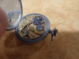 a person holding a pocket watch that is on a table