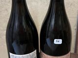 deux bouteilles de vin posées sur un tonneau en bois