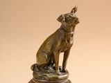 bronze statue of a dog sitting on top of a wooden base