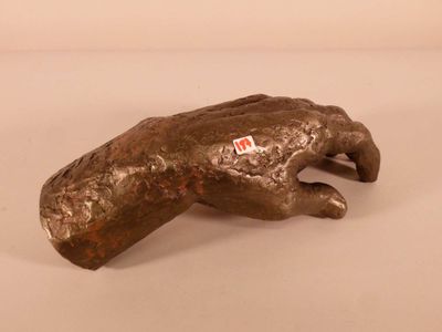 une photo d'une statue en bronze représentant une main sur laquelle est collé un autocollant rouge
