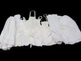 trois robes blanches suspendues à un portant, sur fond noir