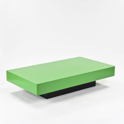 une table basse verte posée sur un plateau blanc