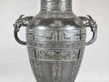 a silver vase that is sitting on a white surface