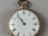 a gold pocket watch with roman numerals on the face