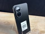 the back of a black cell phone sitting on top of a wooden table