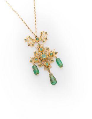 a gold and emerald necklace with a dangling pendant