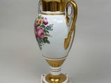 a white vase with a gold handle and flowers on it