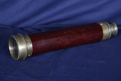 Un vieux télescope est posé sur un tissu bleu.