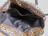 a leopard print bag with a black handle on a wooden table